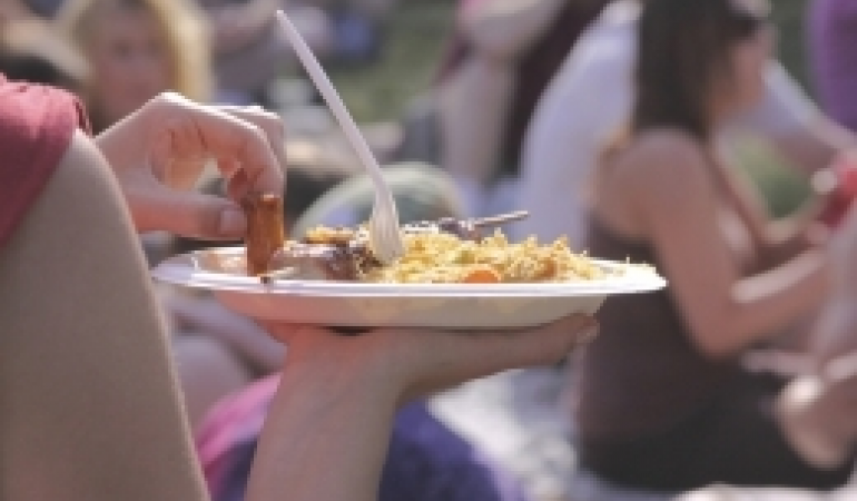 vrouw eet bbq maaltijd van plastic bord in open lucht