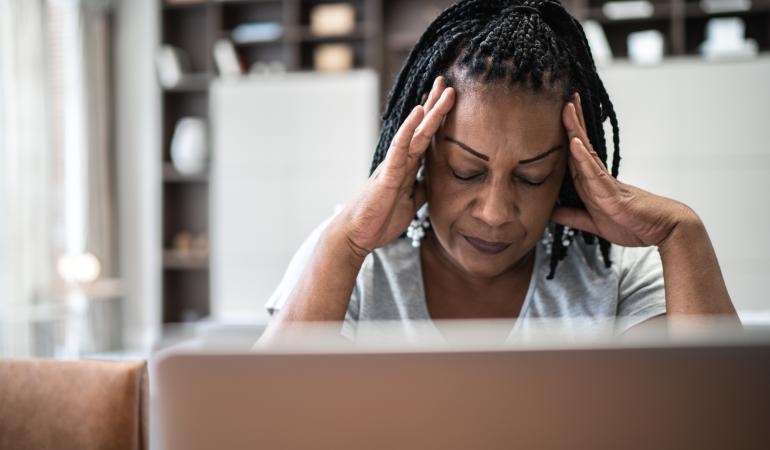  Vrouw met hoofdpijn voor laptop thuis