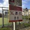 Tijdelijk bord van de gemeente Den Haag, bevestigd aan een paal bij een sportveld, dat wijst op de maatregelen die zijn genomen in het kader van de aanpak van het coronavirus.