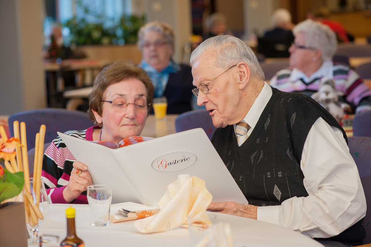 Twee oudere mensen kijken samen naar de menukaart