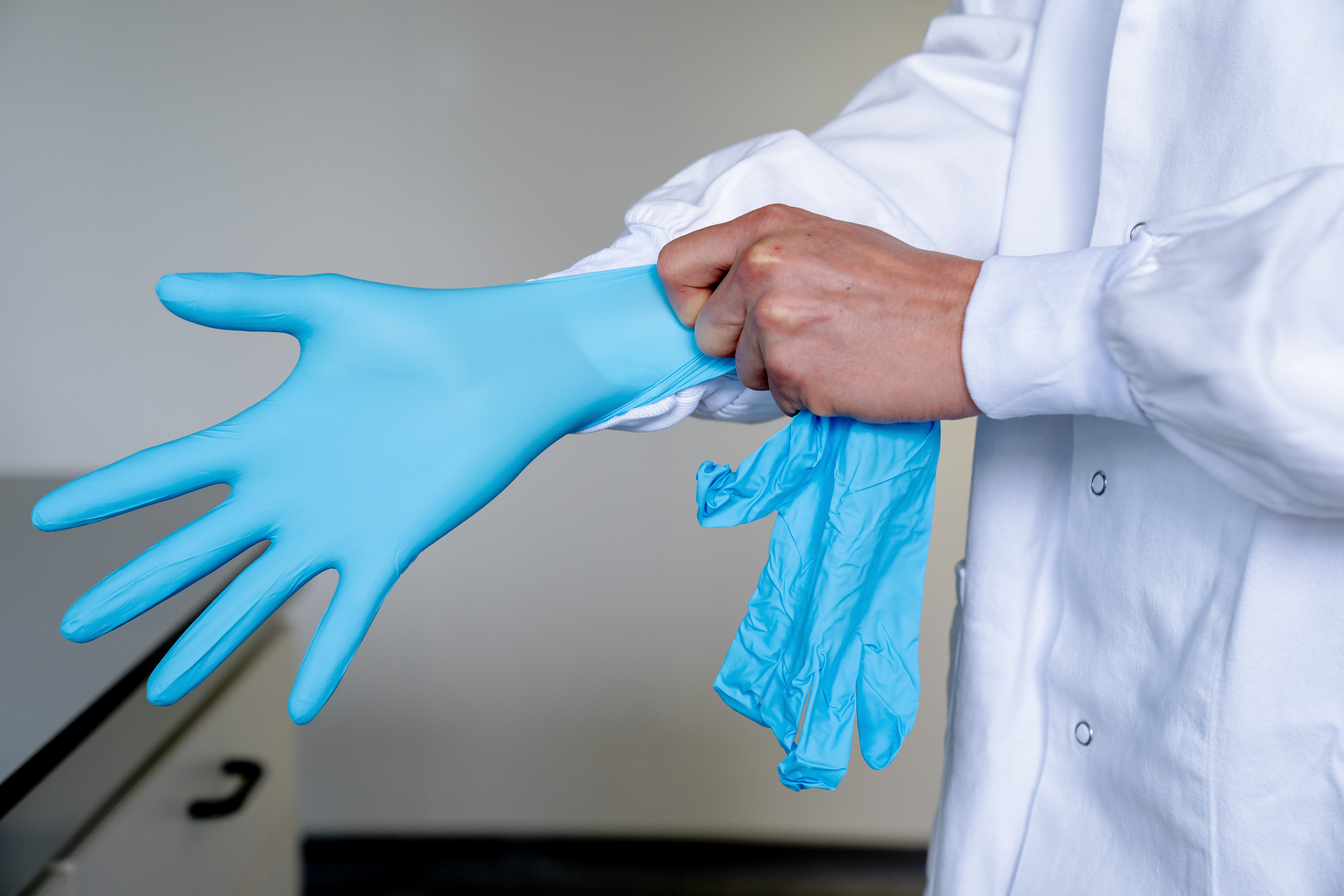 Laborant trekt blauwe handschoenen aan 