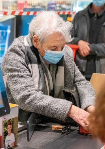 Oudere vrouw betaalt bij supermarkt