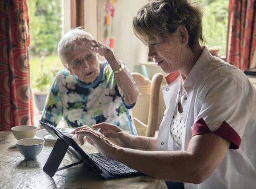 Zorgmedewerker maakt gebruik van digitale middelen tijdens het werk in de ouderenzorg.
