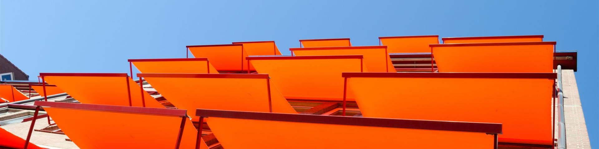 Oranje zonneschermen uitgeklapt boven ramen van woonhuis