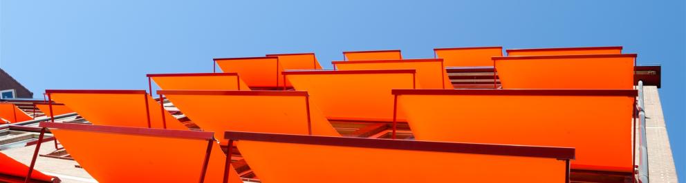 Oranje zonneschermen uitgeklapt boven ramen van woonhuis