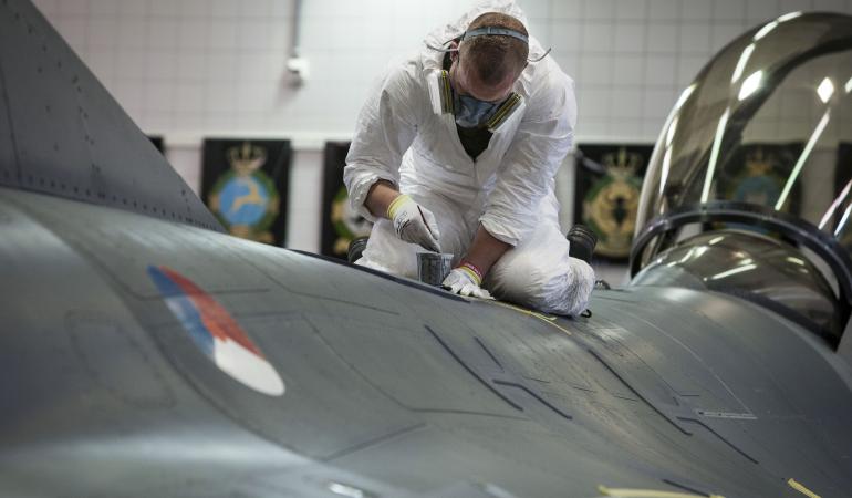 Een persoon bij Defensie verft een vliegtuig met mogelijk chroom-houdende verf