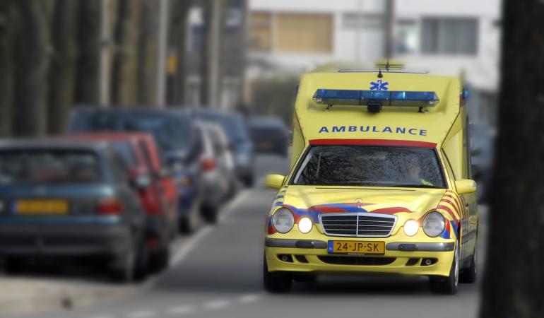 Ambulance rijdt door straat met zwaailicht
