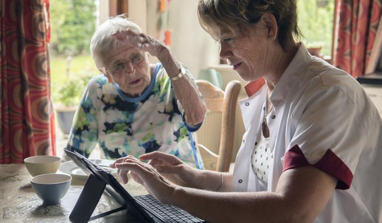 Nurse uses digital device for registering patient data at elderly home
