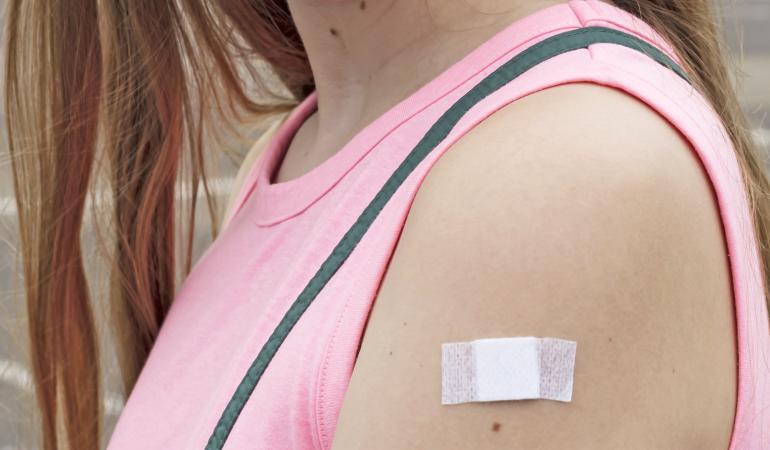 Vrouw met pleister op arm na vaccinatie