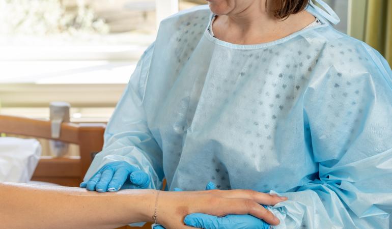Schurft behandelen in een zorginstelling - vrouw met handschoenen smeert patient met creme in 