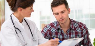 Arts geeft uitleg aan jonge mannelijke patiënt