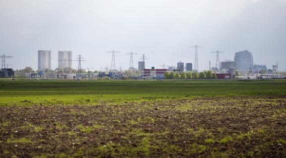 landschap met lanbouwgrond en bebouwing op de achtergrond