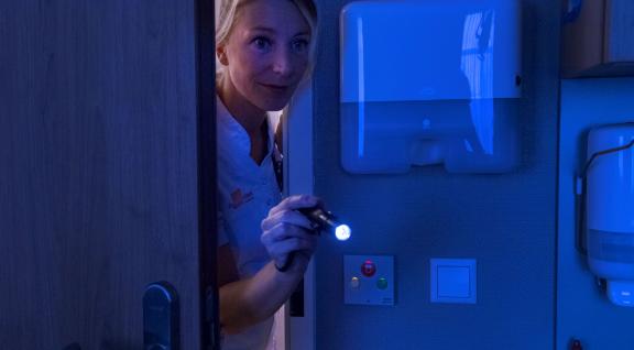 Verpleegster schijnt met nachtlampje in ziekenhuiskamer