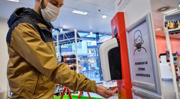 Man desinfecteert handen in winkel