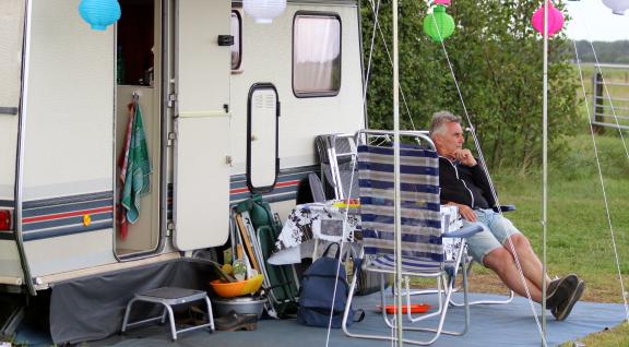 Man zit voor zijn caravan
