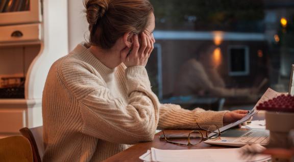 Vrouw achter bureau met laptop en staart uit het raam