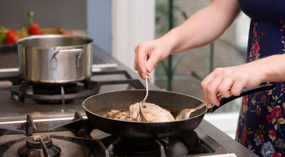 Vrouw bakt vlees in een koekenpan