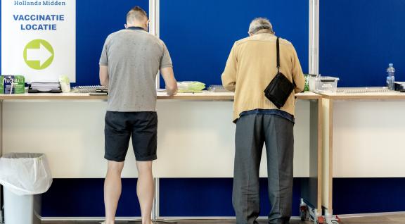 Twee mannen vullen gezondheidsverklaring in bij GGD