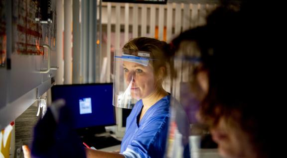 Een zorgmedewerker tijdens nachtdienst met covid gezichtsbescherming op