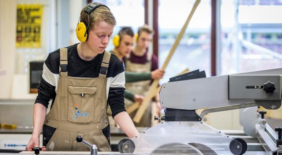 Jongen aan het werk met een zaagmachine