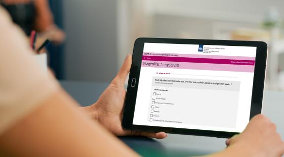 Man houdt tablet vast met vragenlijst over Long COVID