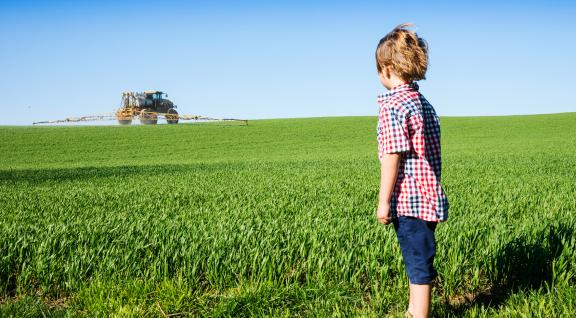 Kind kijkt naar trekker op weiland