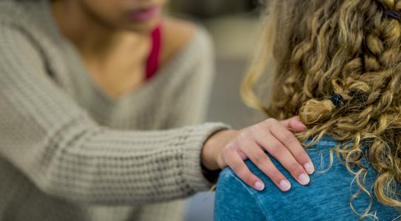 Meisje legt hand op schouder van ander meisje
