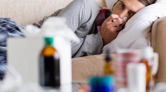 Griepepidemie - man ligt met zakdoek op bank