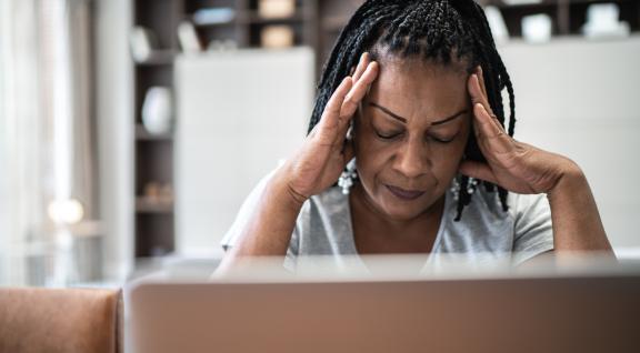  Vrouw met hoofdpijn voor laptop thuis