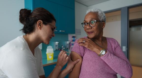 vrouw krijgt de pneumokokkenprik in haar bovenarm
