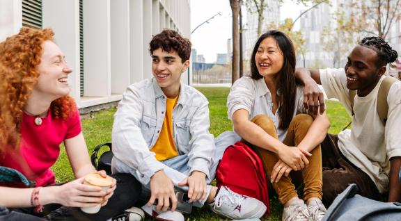 4 Jongeren zitten met elkaar in gesprek, op het gras