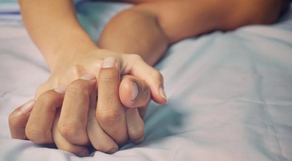 Twee handen verstrengeld op bed - soa-thermometer