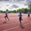 4 jongeren aan het hardlopen op een atletiekbaan