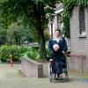 Man duwt rolstoel met bejaarde vrouw langs een kerk