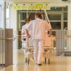 Verpleger rijdt ziekenhuisbed door gang van ziekenhuis