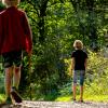 Twee jongens wandelen over een bospad in de zomer.