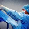 OK-Assistente helpt een collega in beschermende schort op de operatiekamer