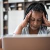  Vrouw met hoofdpijn voor laptop thuis