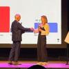 Op de foto ontvangt Hester Coppoolse de prijs uit handen van Jim van Steenbergen. Rechts staat Monica Wong, voorzitter van de jury.